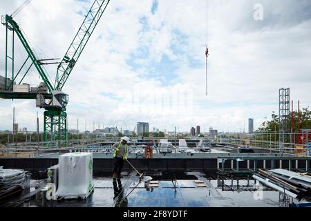 Bauarbeiter fegt Regen vom Dach der Baustelle mit Blick auf london einschließlich london Eye und Houses of parliament Im Hintergrund Stockfoto