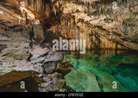 Höhle mit türkisfarbenem, ruhigem Wasser im Inneren und Steinmauern Stockfoto