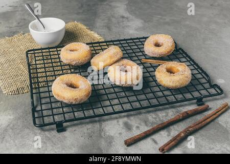 Gezuckerte Mini-Donuts mit Zimt auf einem Kühlgestell Ein grauer Hintergrund Stockfoto