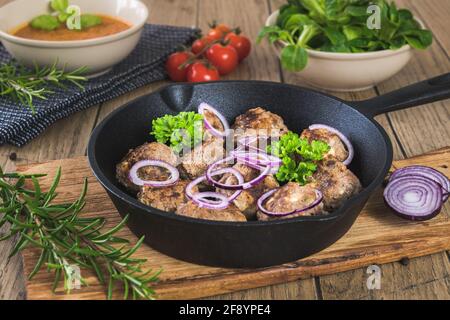 Fleischbällchen mit Feta-Käse in einer gusseisernen Pfanne auf einem Rustikaler Holztisch Stockfoto