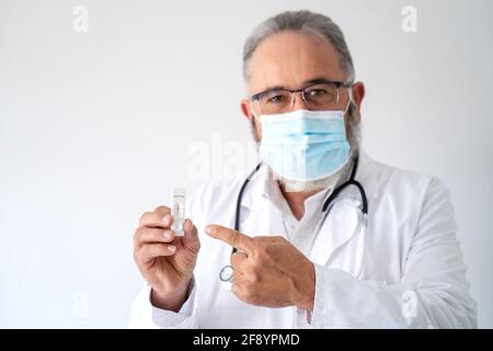 Porträt eines leitenden Arztes in einer OP-Maske mit Covid-19 PCR-Ergebnis. Stockfoto