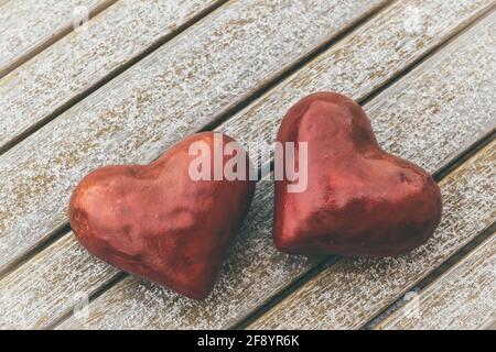 Zwei rote Herzen auf einem Holztisch, der leicht ist Mit Schnee bedeckt Stockfoto
