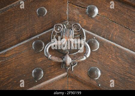 Antiker ringförmiger Klopfer aus Metall an einer mit Holz verzierten Tür Mit Anzeichen von Alterung und Wetter Stockfoto