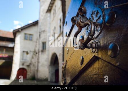 Antiker ringförmiger Klopfer aus Metall an einer mit Holz verzierten Tür Mit Anzeichen von Alterung und Wetter Stockfoto