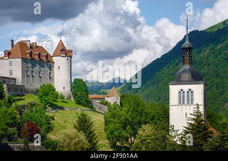 Außenansicht des Dorfes Gruyeres, berühmte Käserei Stadt der schweiz, mit seiner mittelalterlichen Burg und Glockenturm auf der Spitze der Hügel su Stockfoto