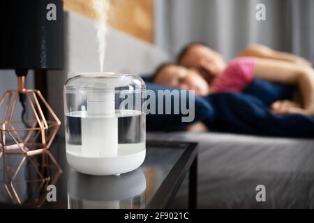 Luftbefeuchter Dampf Auf Nachttisch In Der Nähe Von Junges Paar Schlafen Stockfoto