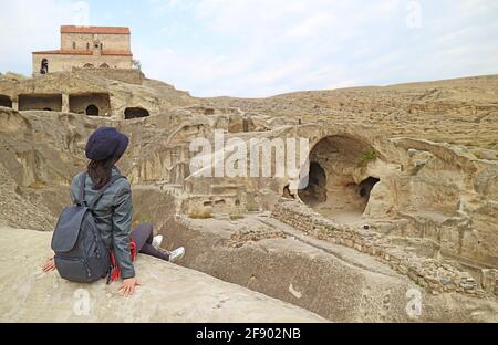 Weibliche Besucherin, die auf den Ruinen der Höhlenstadt Uplistsikhe in der Nähe der Stadt Gori in Georgien sitzt Stockfoto