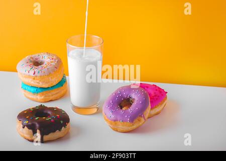 Süße Donuts mit einem Glas ausgiessende Pflanzenmilch Stockfoto