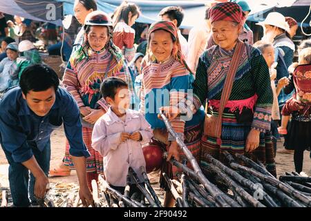 BAC Ha, Vietnam - 4. April 2016: Blume Hmong Stamm in bunten traditionellen Kleidung mit ihrem Kind auf Can CAU Samstag Markt in Vietnam Stockfoto