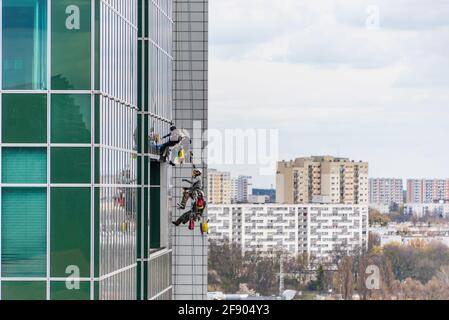 Die Gruppe der Arbeiter, die Fenster und die Glasfassade eines modernen Bürogebäudes reinigen. Die Hochhaus-Fensterputzer Service-Mitarbeiter verwenden spezialisiert Stockfoto