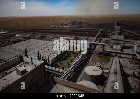 GRES-1 Wärmekraftwerk.Miniaturansicht der Anlage mit neigungsverschobener Unschärfe-Wirkung.Industriegebäude, Speichertanks und Pipeline.Schwarze Rauchwolke Stockfoto