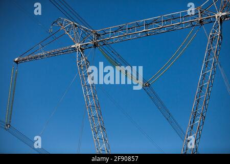 Elektrischer Pylon (Mast) mit Glasolatoren auf klarem blauen Himmel Hintergrund. Nahaufnahme. Stockfoto