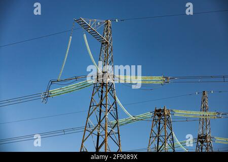 Hochspannungs-Übertragungsleitung elektrischer Turm mit Glasisolatoren am klaren blauen Himmel. Stockfoto