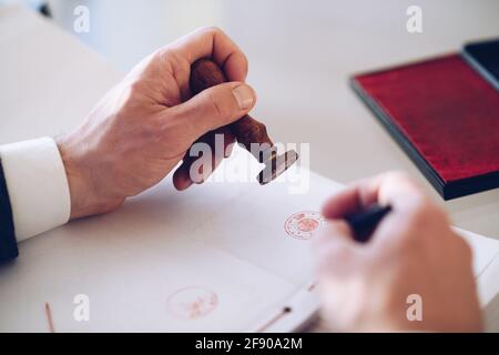 Nahaufnahme des Handstempels einer Person mit genehmigter Stempelmarke auf einem Zertifikat oder einem anderen Dokument. Stockfoto