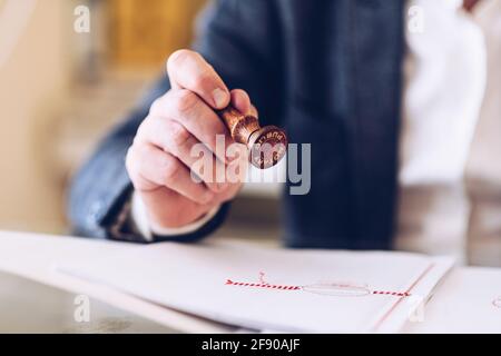 Nahaufnahme eines Notars Handstempelung mit genehmigter Stempel auf Zertifikat oder Dokument öffentlich. Stockfoto