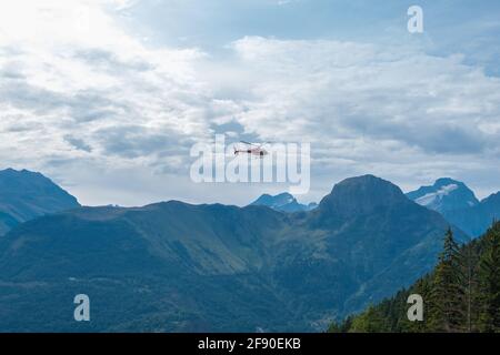 Auris, Isere, Frankreich - 22. August 2019: Panoramablick auf die Alpenlandschaft und Hubschrauber unter den Wolken in den nördlichen Alpen, Departement Isere, Frankreich Stockfoto