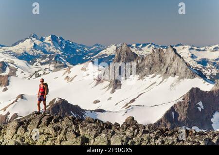 Junge attraktive Rucksacktouristen stehen auf einem felsigen Kamm mit Blick auf die Berge Stockfoto