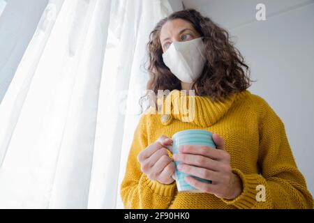 Weiße Frau mit Maske isoliert zu Hause für Virus Ausbruch Stockfoto