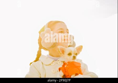 Porträt eines glücklichen Teenagers mit ihrem kleinen chihuahua-Hund. Ein Mädchen auf dem Hintergrund der Natur umarmt ihren Chihuahua Hund in Kleidung. Stockfoto