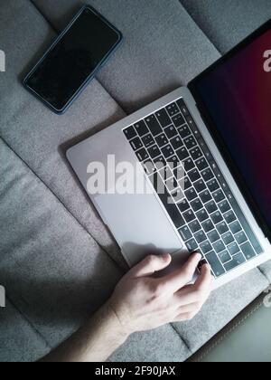 Die Hand des Mannes auf der Laptop-Tastatur. Smartphone. Draufsicht. Stockfoto