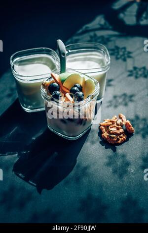 Joghurt mit Früchten im Glas auf schwarzem Tisch Stockfoto