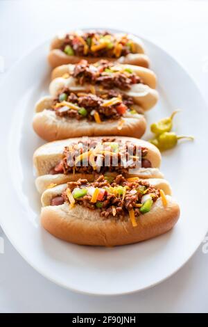 Nahaufnahme eines Tellers mit Chili-Hunden auf einer Theke aus weißem Marmor. Stockfoto