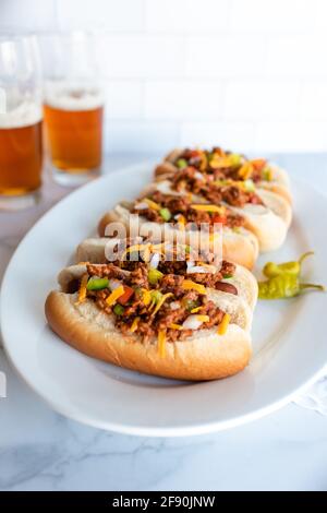 Nahaufnahme eines Tellers mit Chilli-Hunden mit Gläsern Bier im Hintergrund. Stockfoto