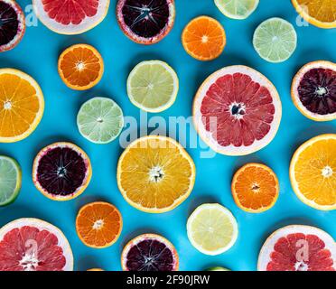 Bunte Scheiben verschiedener Zitrusfrüchte auf blauem Hintergrund. Stockfoto