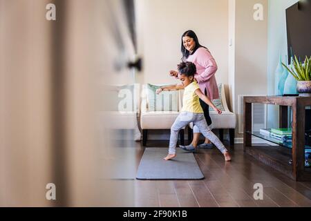 Mädchen tanzt mit lächelnder Großmutter zu Hause Stockfoto