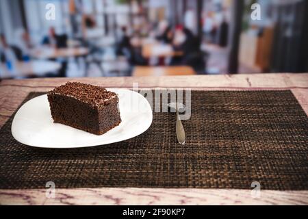 Scheibe Schokoladenkuchen mit Schokoladenstückchen auf Holz Tisch in einem Restaurant Stockfoto