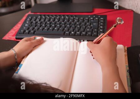 Eine ziemlich lateinische Frau mittleren Alters schreibt in ihrem Arbeitsraum Stockfoto