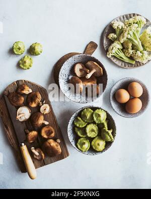 Ein Flatlay aus Shitaake-Pilzen, Pattypan-Kürbis und Baby-Caulini mit frischen Eiern vom Bauernhof. Stockfoto