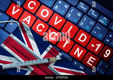 COVID-19-Immunisierung in Großbritannien mit Spritze und Gesichtsmaske mit britischer Flagge und Impfhinweis auf der Computertastatur. Konzept der Covid-Impfung bei Stockfoto