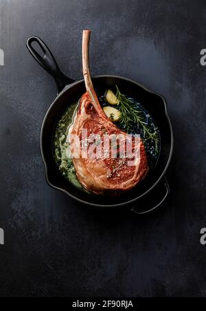 Rohes frisches Fleisch Tomahawk Steak in gusseiserner Pfanne Auf dunklem Hintergrund Stockfoto