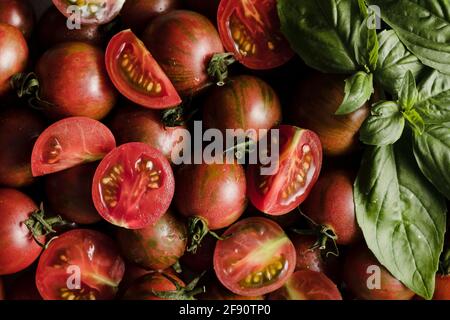Ganze und in Scheiben geschnittene Kirschtomaten in einer Schüssel. Stockfoto