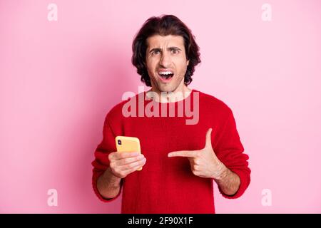 Porträt von verärgerten Brunet Kerl in den Händen halten Demonstratieren Gerät Fake News isoliert über rosa Hintergrund Stockfoto