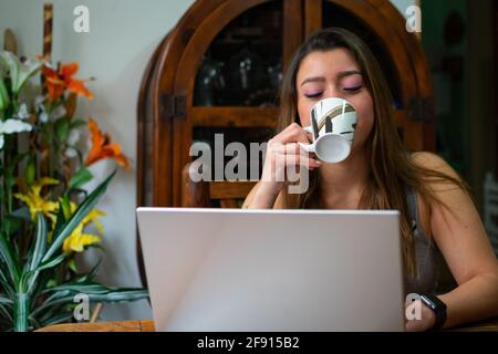 Studentin trinkt Kaffee sitzen in einem Stuhl - Konzept Der Schüler, die Online-Kurse besuchen Stockfoto