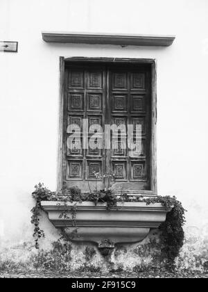 Graustufen-Aufnahme von ornamentierten Vintage-Fensterläden aus Holz mit einer Außenseite Fensterbank Stockfoto