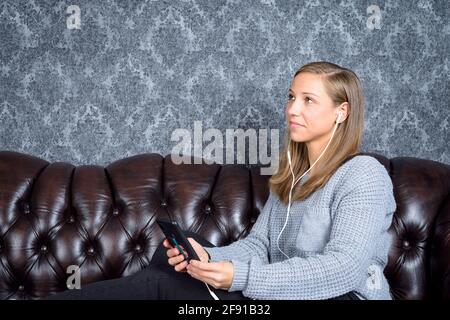 Ein nachdenklicher, glücklicher Student sitzt und hört Musik Stockfoto