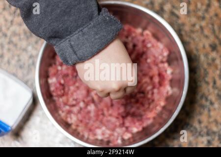 Der Schuss eines Kochs, der dem Hackfleisch Salz hinzufügt In einer Schüssel Stockfoto