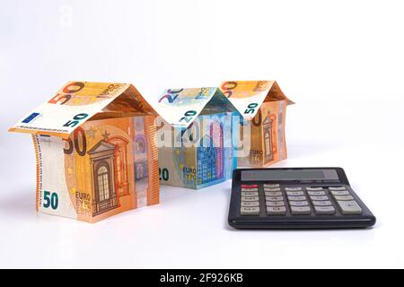 Hütten aus 50 und 20 Euro-Banknoten und ein Rechner isoliert auf einem hellen Hintergrund, Nahaufnahme Stockfoto