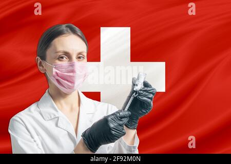 Ärztin bereitet die Impfung vor dem Hintergrund der Schweizer Flagge vor. Impfkonzept Schweiz. Stockfoto