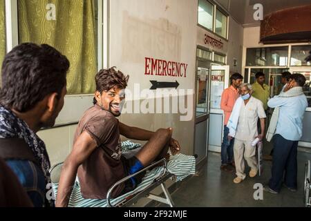 Ein junges Unfallopfer in recht gutem Geist wartet vor der Notaufnahme eines ländlichen Krankenhauses in Rajasthan, Indien Stockfoto