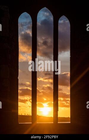 Timoleague, West Cork, Irland. April 2021. Die Sonne geht spektakulär über dem Franziskanerkloster in Timoleague auf als Auftakt zu einem überwiegend trockenen Tag mit trüben Sonnenstrahlen. Die Abtei wurde 1240 gegründet und überlebte, bis sie 1642 von englischen Soldaten verbrannt wurde. Quelle: AG News/Alamy Live News Stockfoto