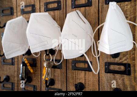 ffp2-Gesichtsmasken, die an Haken an einem Holzschlüssel hängen Halter Stockfoto