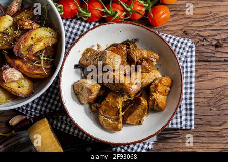 Appetitliches Eintopf aus Schweinefilet, im Wok gegarten, in Würfel geschnitten. Mit gerösteten und goldenen Kartoffeln, Knoblauch, Salz, Orangano und frischen Tomaten. Stockfoto