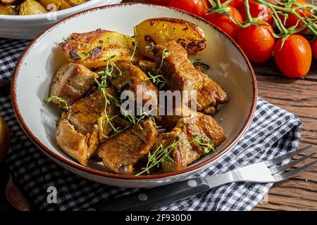 Appetitliches Eintopf aus Schweinefilet, im Wok gegarten, in Würfel geschnitten. Mit gerösteten und goldenen Kartoffeln, Knoblauch, Salz, Orangano und frischen Tomaten. Stockfoto
