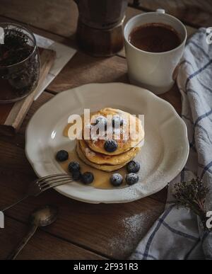 Köstliche hausgemachte Käsekuchen mit Honig beträufelt und mit frischen Heidelbeeren bestreut, auf einem hölzernen Hintergrund Stockfoto