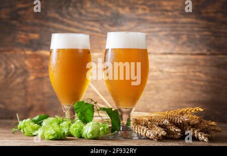 Gläser Bier, Weizenohren und Hopfen auf einem hölzernen Hintergrund Stockfoto