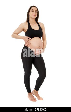 Sportliche junge hispanische Schwangerin voller Länge über weiß Hintergrund Stockfoto
